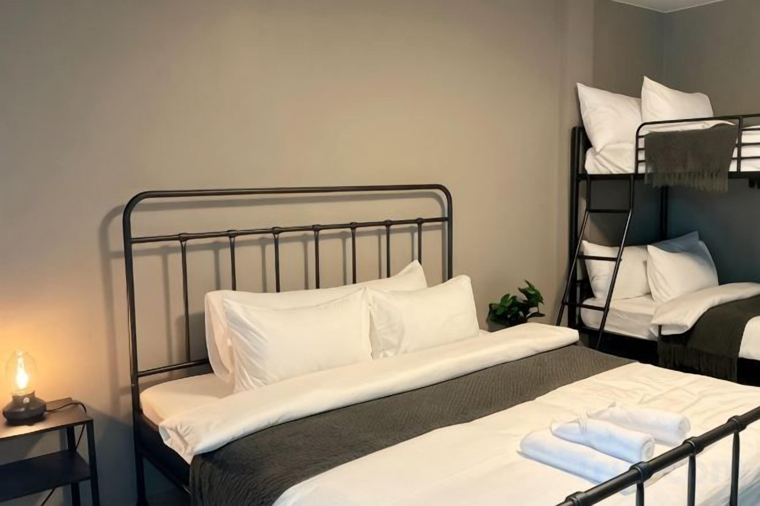 Un letto singolo con struttura in metallo, biancheria da letto bianca e un comodino con una lampada.