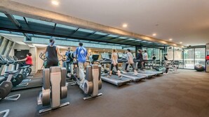 Une salle de sport équipée de tapis de course, de vélos elliptiques et de poids libres.