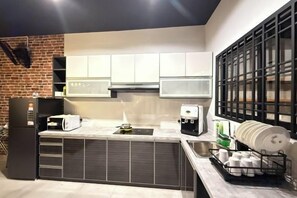 Una cocina moderna con refrigerador incorporado, cafetera y escurreplatos.