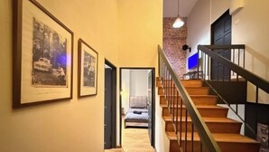 Eine Treppe mit Holzboden und Metallgeländern führt zu einem Schlafzimmer mit einem Bett und einem Nachttisch.