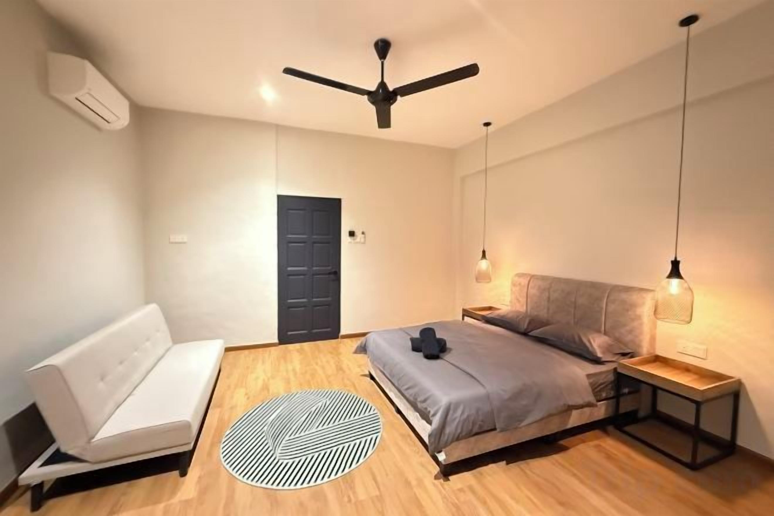 A bedroom with a bed, a sofa, a ceiling fan, and a door.