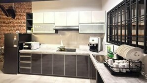 Eine moderne Küche mit weißen Schränken, einem schwarzen Kühlschrank und einer Kaffeemaschine.
