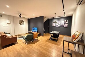 Una sala de estar moderna con mesa de billar, televisor y un espacio de estar acogedor.