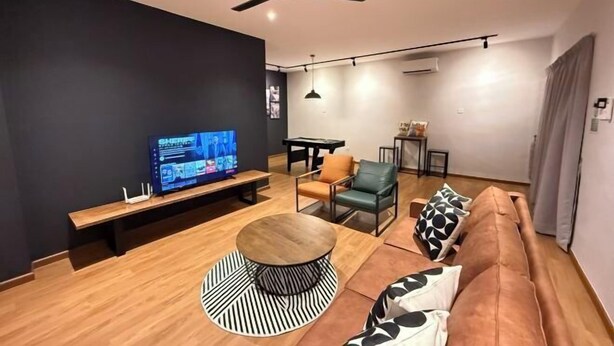 Ein modernes Wohnzimmer mit Fernseher, Deckenventilator, rundem Couchtisch, Sofa und Esstisch.
