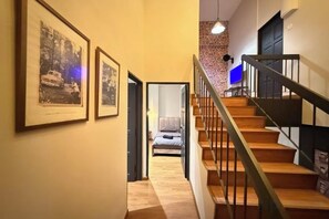 Una escalera de madera con barandillas de metal que lleva a un dormitorio con cama y televisor.