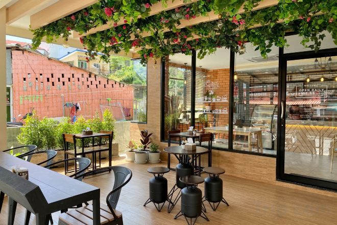 An outdoor seating area with tables and chairs, a brick wall, and a view of a store through large windows.