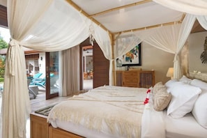 A bedroom with a canopy bed, wooden furniture, a view of the outdoor area, and a painting on the wall. - Villa Liang Ubud (Bali)