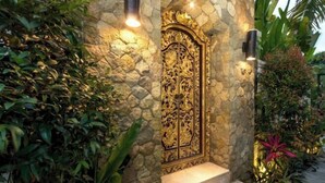 A stone wall with a decorative golden door and steps leading up to it. - Villa Liang Ubud (Bali)