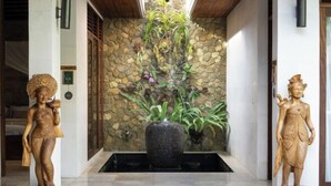 A reception area with two wooden statues, a stone wall, and a water feature.