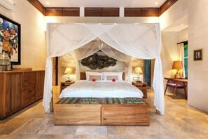 A bedroom with a canopy bed, wooden headboard, bedside tables with lamps, and a decorative wall piece. - Villa Liang Ubud (Bali)