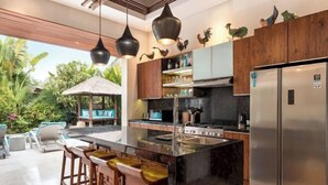 A modern kitchen with a central island, stainless steel appliances, and a view of the outdoors. - Villa Liang Ubud (Bali)