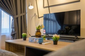 A modern living room with a flat-screen TV, a wooden coffee table, and small potted plants. - Arte Cheras by KL Innfinity Stay (Kuala Lumpur)