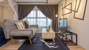 A modern living room with a grey sofa, a wooden coffee table, and a TV stand. - Arte Cheras by KL Innfinity Stay (Kuala Lumpur)