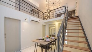 A dining area with a table set for four, a staircase, and a second-floor balcony. - Arte Cheras by KL Innfinity Stay (Kuala Lumpur)