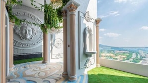 A balcony with a patterned floor, decorative columns, and a view of the city. - Arte Cheras by KL Innfinity Stay (Kuala Lumpur)
