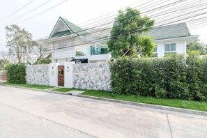A modern two-story house with a stone wall, a green lawn, and a paved driveway. - 9 bedroom Stylish 2-Villa Combination by Hi At Home (Pattaya)