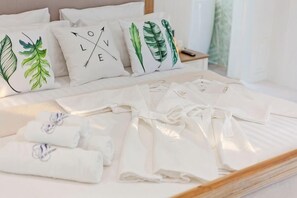 A neatly made bed with white linens and pillows featuring leaf designs. - 9 bedroom Stylish 2-Villa Combination by Hi At Home (Pattaya)