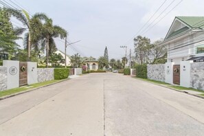 A residential street with houses, a gated entrance, and a clear sky. - 9 bedroom Stylish 2-Villa Combination by Hi At Home (Pattaya)