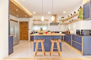 Een moderne keuken met een centraal eiland, barkrukken en inbouwapparatuur.