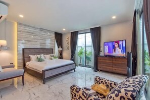 A modern bedroom with a large bed, a television, and a sofa. - 9 bedroom Stylish 2-Villa Combination by Hi At Home (Pattaya)