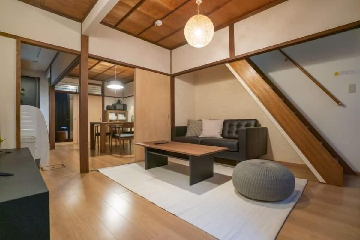 Ein modernes Wohnzimmer mit Holzboden, einer Couch, einem Couchtisch und einer Pendelleuchte.