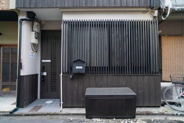 Un edificio con cerca de madera oscura, un buzón y una bicicleta estacionada afuera.