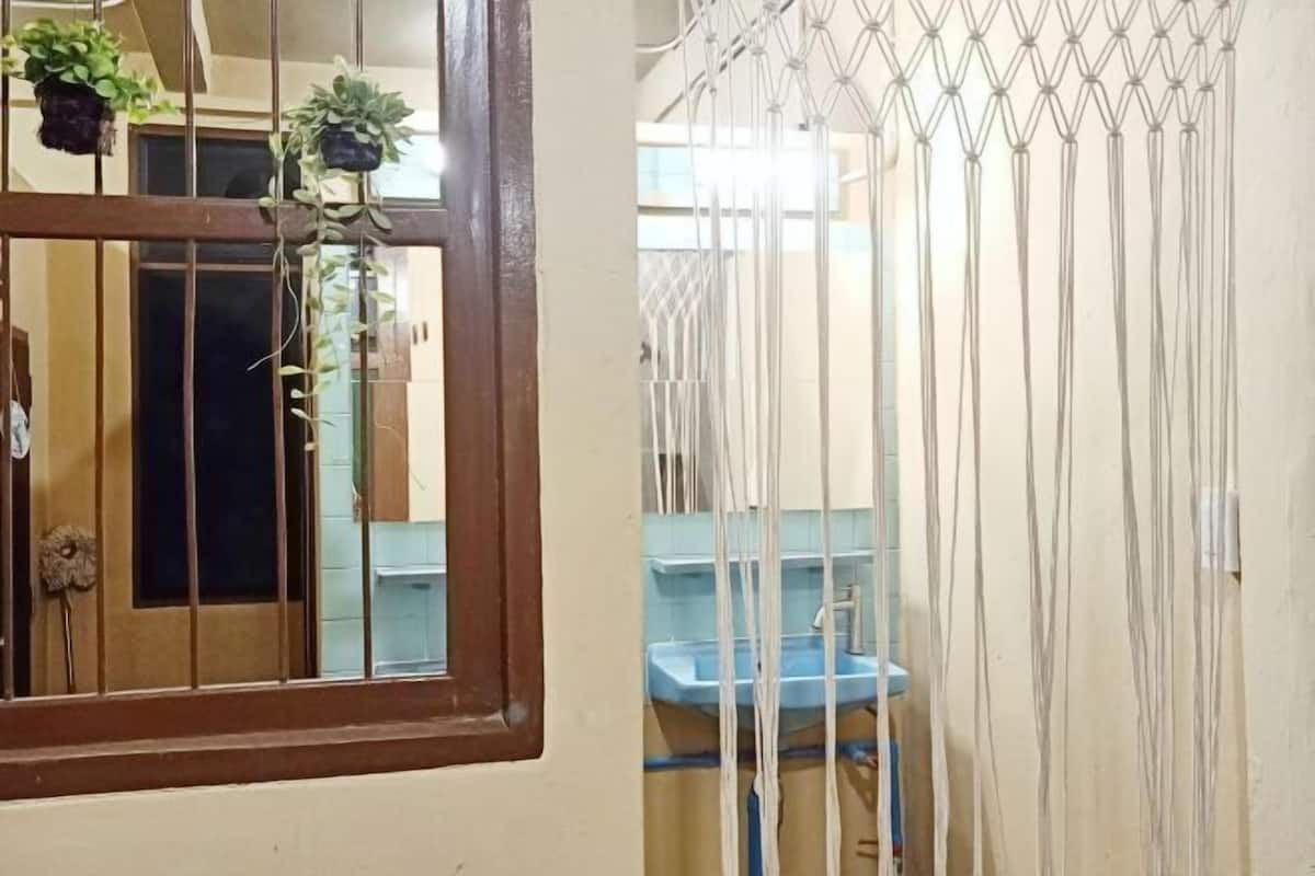 A bathroom with a blue sink, a window with a wooden frame, and a curtain with a geometric pattern.