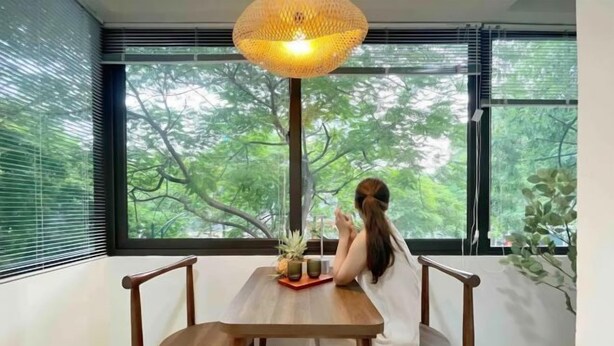 A room with a wooden table, two chairs, a potted plant, and a window with blinds. - OH Trendy homes Hoan Kiem LTK Bancony City view (Hanoi)
