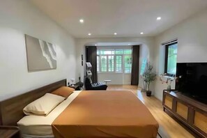 A hotel room with a large bed, a television, a desk, and a window with curtains. - OH Trendy homes Ly Thuong Kiet (Hanoi)