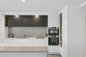 A modern kitchen with white cabinetry, a tiled backsplash, and built-in appliances including a Bosch oven and microwave.