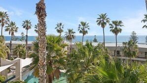 A resort with a pool, palm trees, and a view of the ocean.