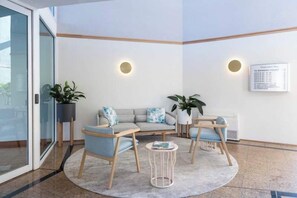 A modern waiting area with a sofa set, two chairs, a small table, and potted plants.