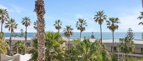 Un resort con piscina, palmeras y vista al océano.
