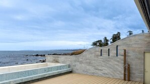 Um deck de madeira com um muro de pedra e vista para o mar.