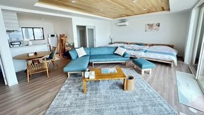 Uma sala de estar moderna com um sofá seccional, uma mesa de centro de madeira e um tapete cinza.