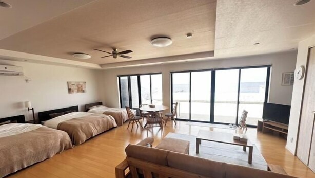 A hotel room with a large bed, a sofa, a dining table, and a TV. - Lapita Resort (Sakai)