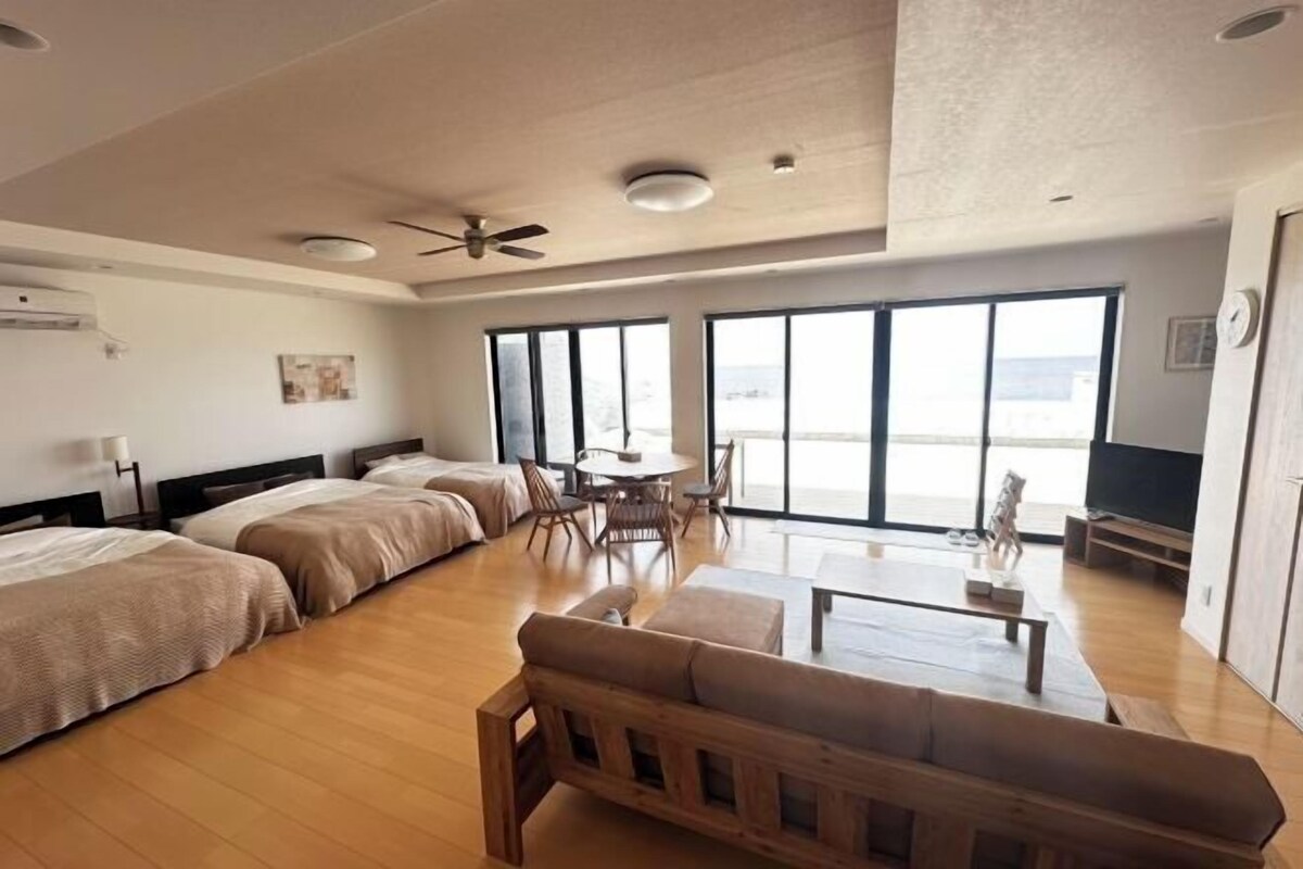 A hotel room with a large bed, a sofa, a dining table, and a TV.