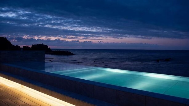 Piscina com vista para o oceano ao entardecer.