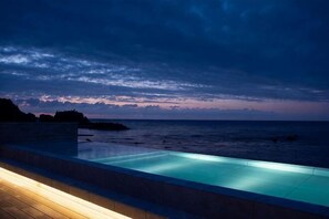 Une piscine avec vue sur l’océan au crépuscule.