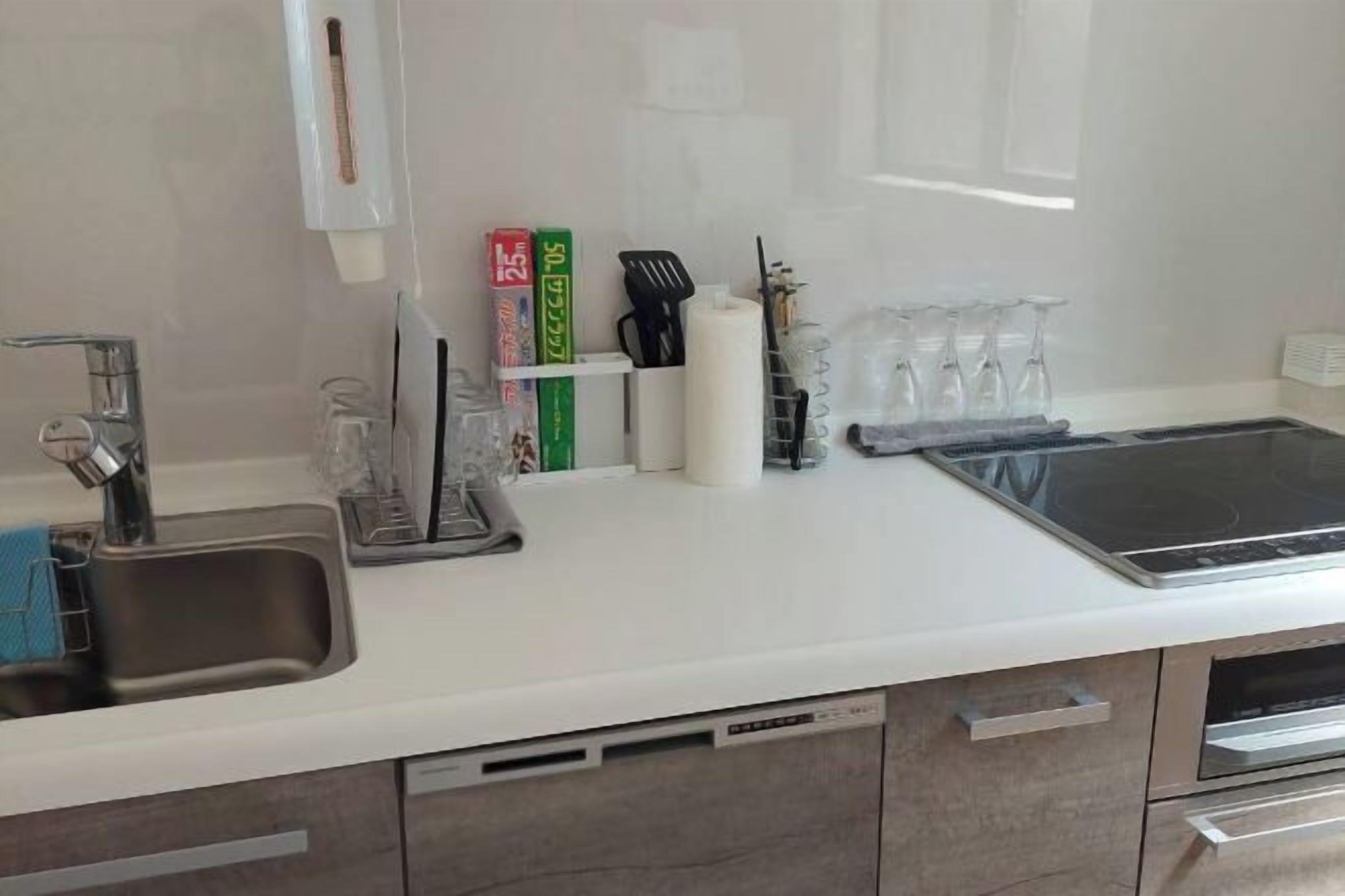 Una cocina moderna con un lavamanos de acero inoxidable, una encimera blanca y un horno empotrado.