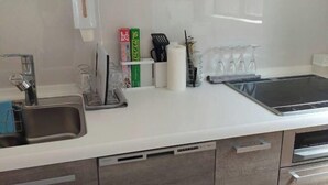 A modern kitchen with a stainless steel sink, a white countertop, and a built-in oven. - Lapita Resort (Sakai)