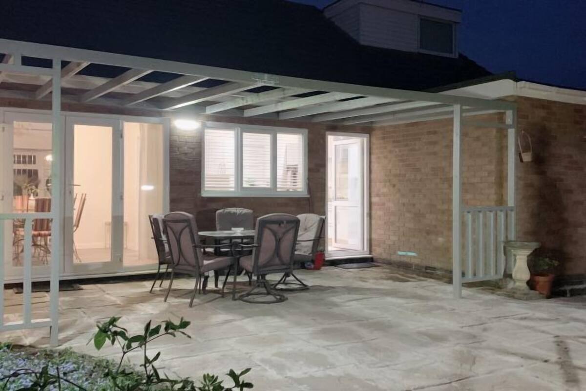 An outdoor patio with a covered seating area, a brick wall, and a white pergola.