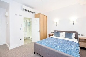 A bedroom with a bed, a wardrobe, a bathroom, and a shower. - Eldon Chambers Pod 1 by City Living London (London)