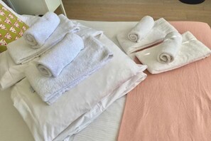 A neatly made bed with folded towels and a pink blanket. - Eldon Chambers Pod 1 by City Living London (London)