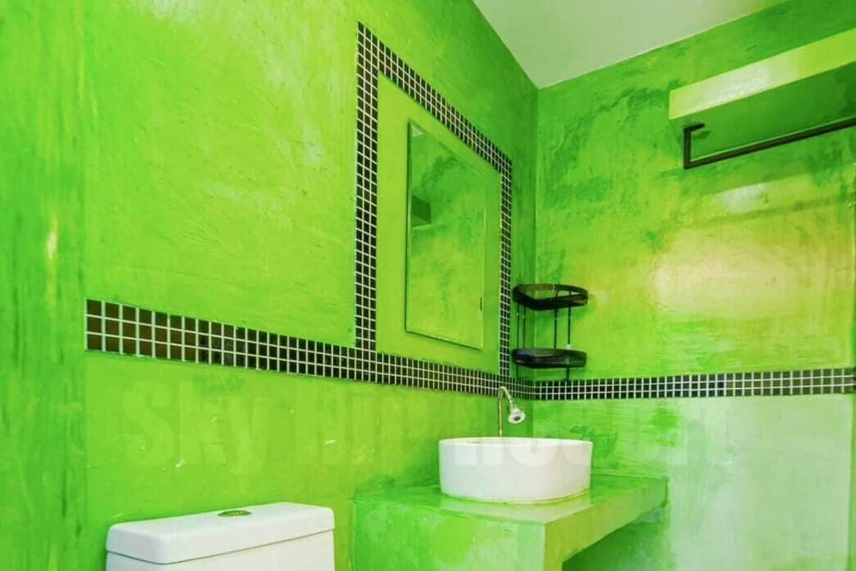 A bathroom with a green wall, a white toilet, a white sink, and a mirror.