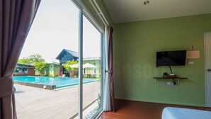 A hotel room with a large window, a TV mounted on the wall, and a bed.