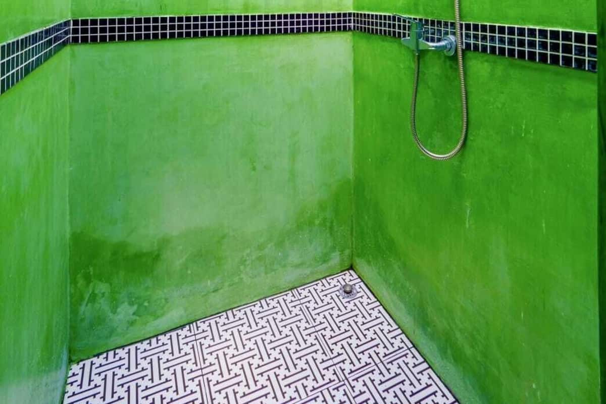 A bathroom with green walls, a shower, and a patterned floor.