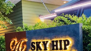 A sign for Sky Hip Resort & Sports Club with illuminated lettering.