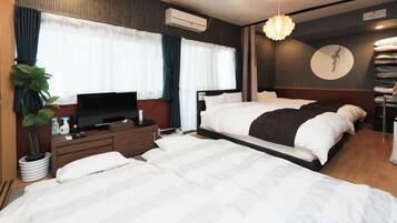 A hotel room with a large bed, a TV, a bedside table, and a potted plant.
