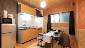A compact kitchen with a microwave, stove, and wooden cabinets. - Prosupa 5th #501 (Nagoya)